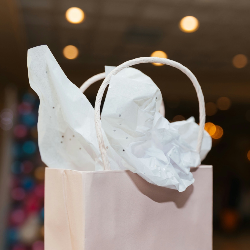 Elegancka różowa torebka prezentowa z białą bibułą jako element idealnego pakietu powitalnego dla nowego pracownika w biurze